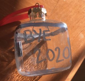 A glass ornament has "Bye 2020" written on it with silver sharpie